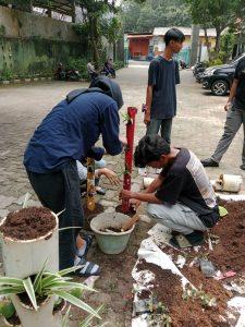 Mahasiswa sedang membuat vertikal garden dalam paralon